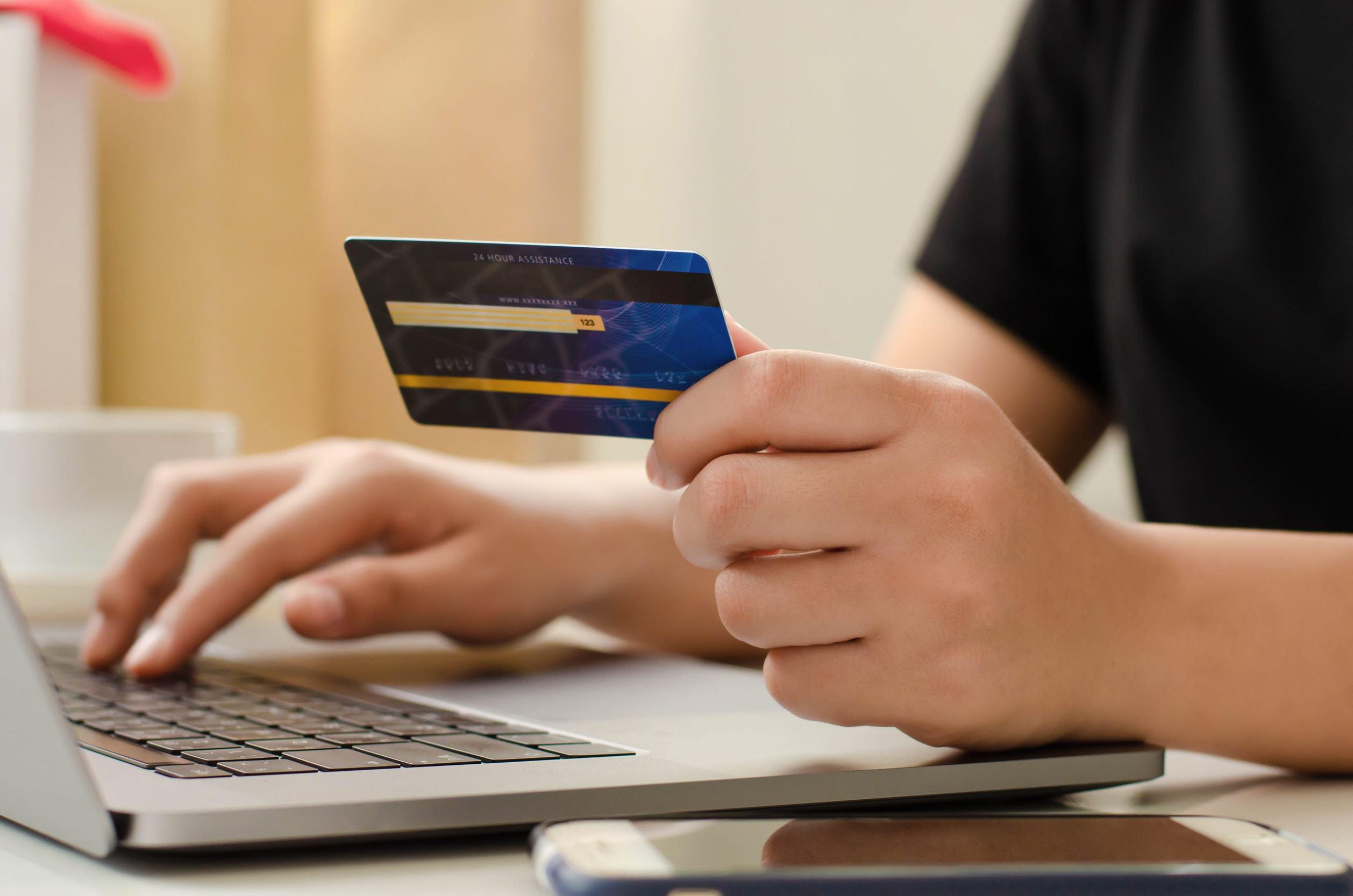 A Person Holding A Credit Card And Using A Laptop