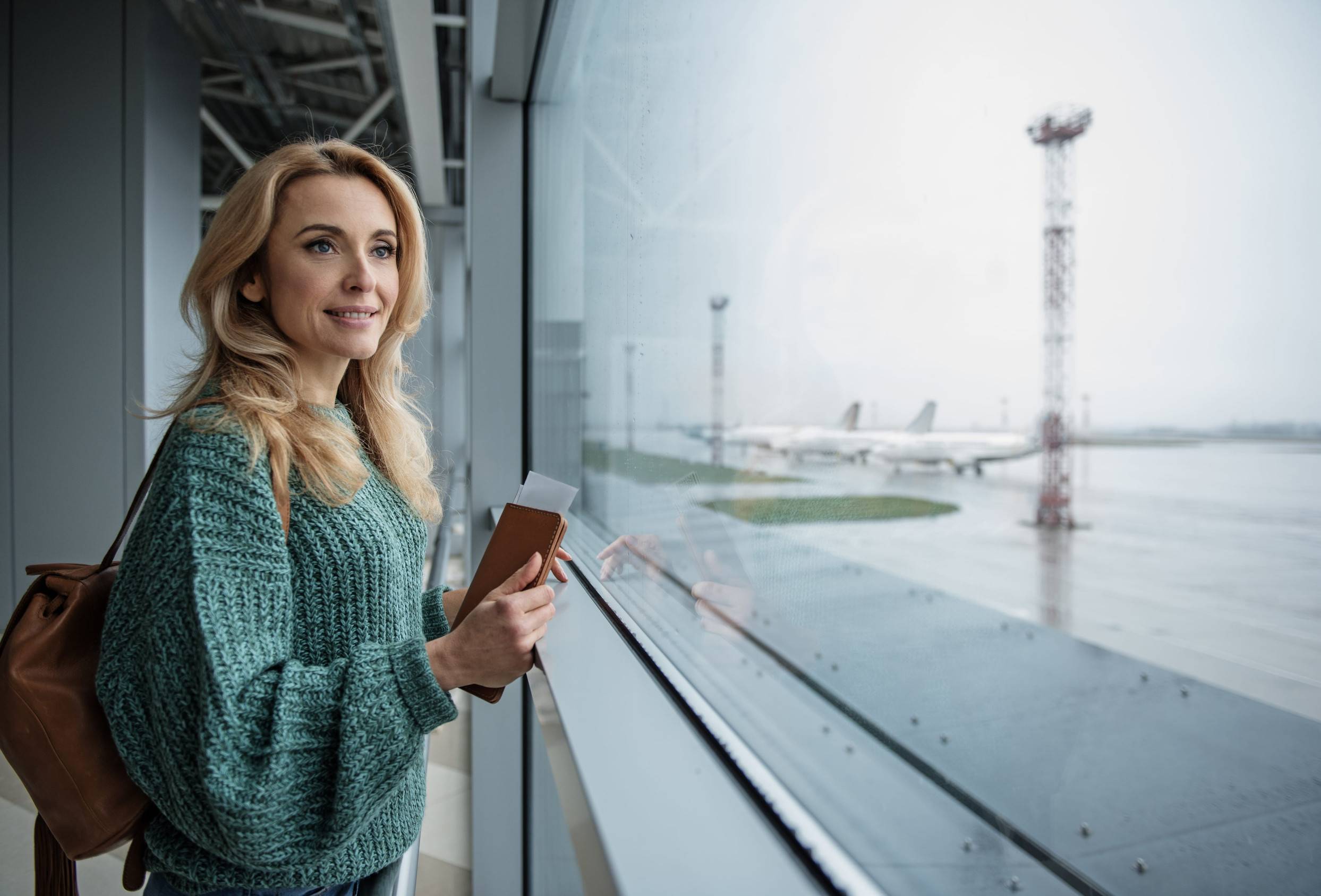 Woman Holding Passport And Boarding Pass At Airport Terminal